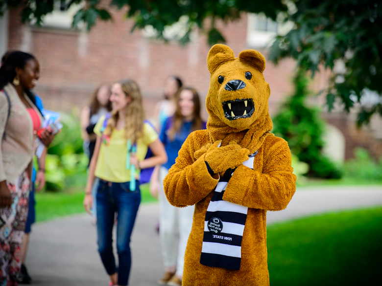 Lion Mascot stands while students walk behind