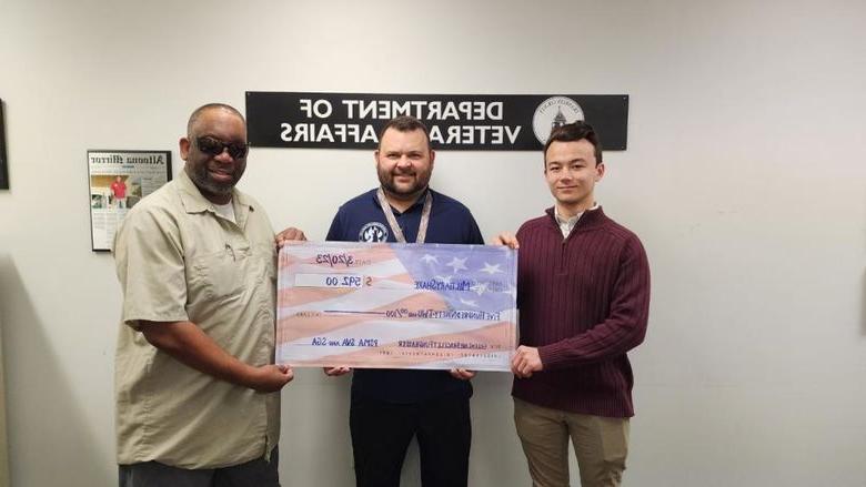 Students hold a check written out to MilitaryShare Program
